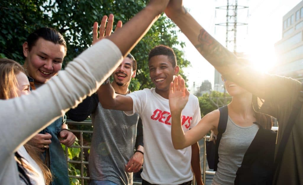 A group of friends high-fiving, laughing, and smiling