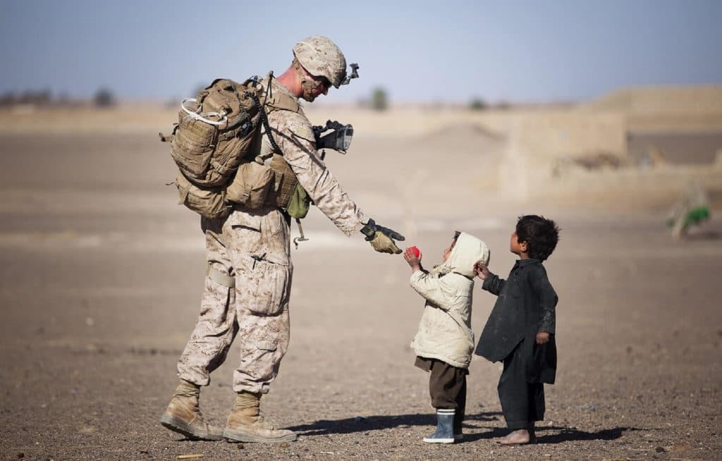 An American soldier handing food to a child