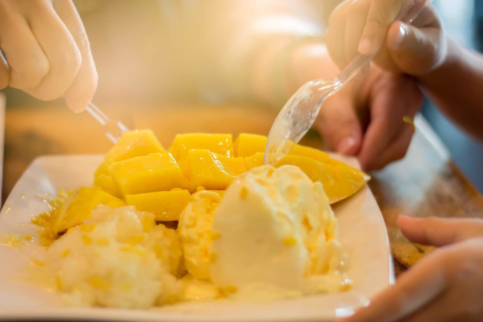 People scooping out a mango flavored ice cream