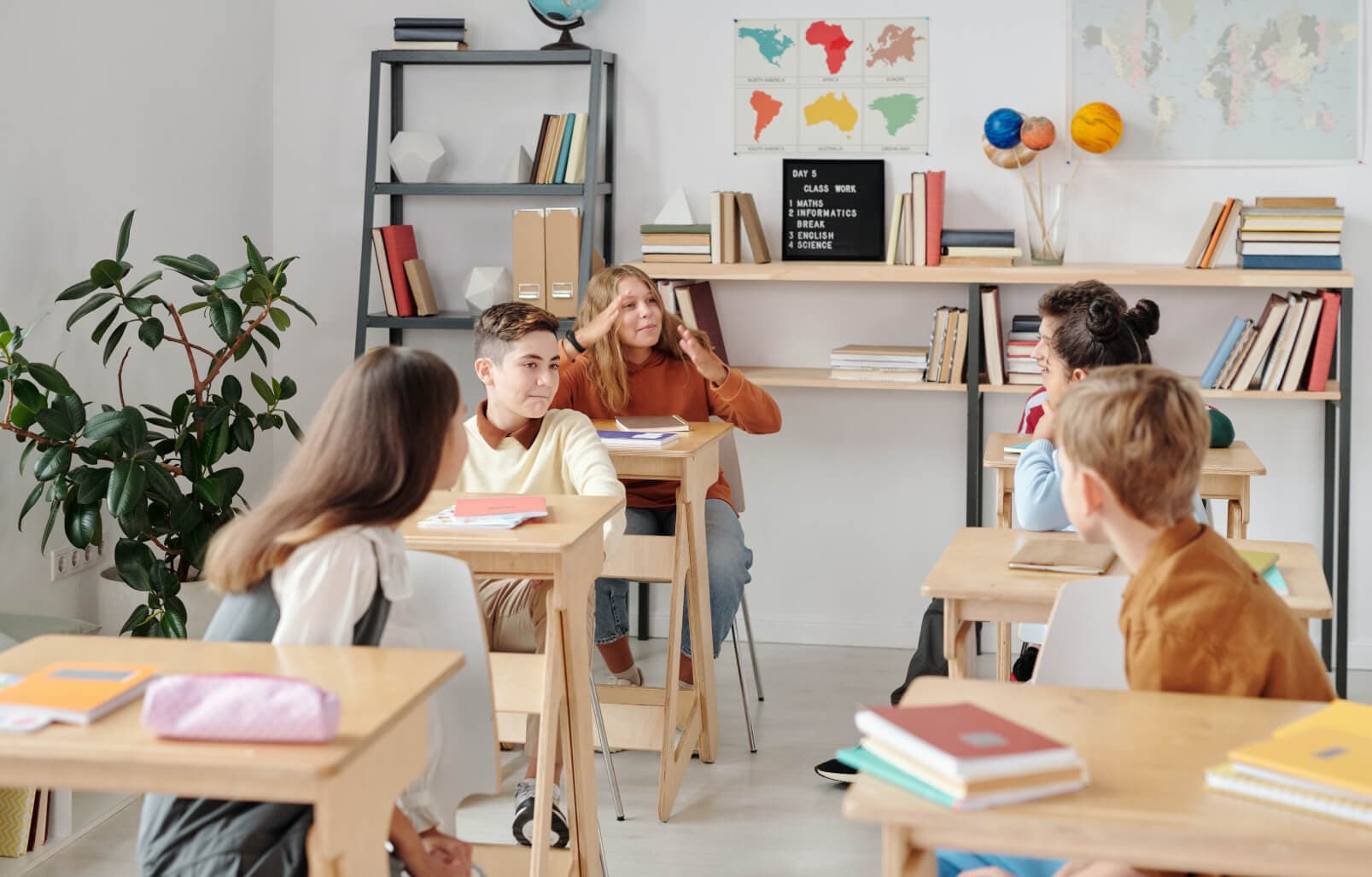 A classroom with books, desks, and six children