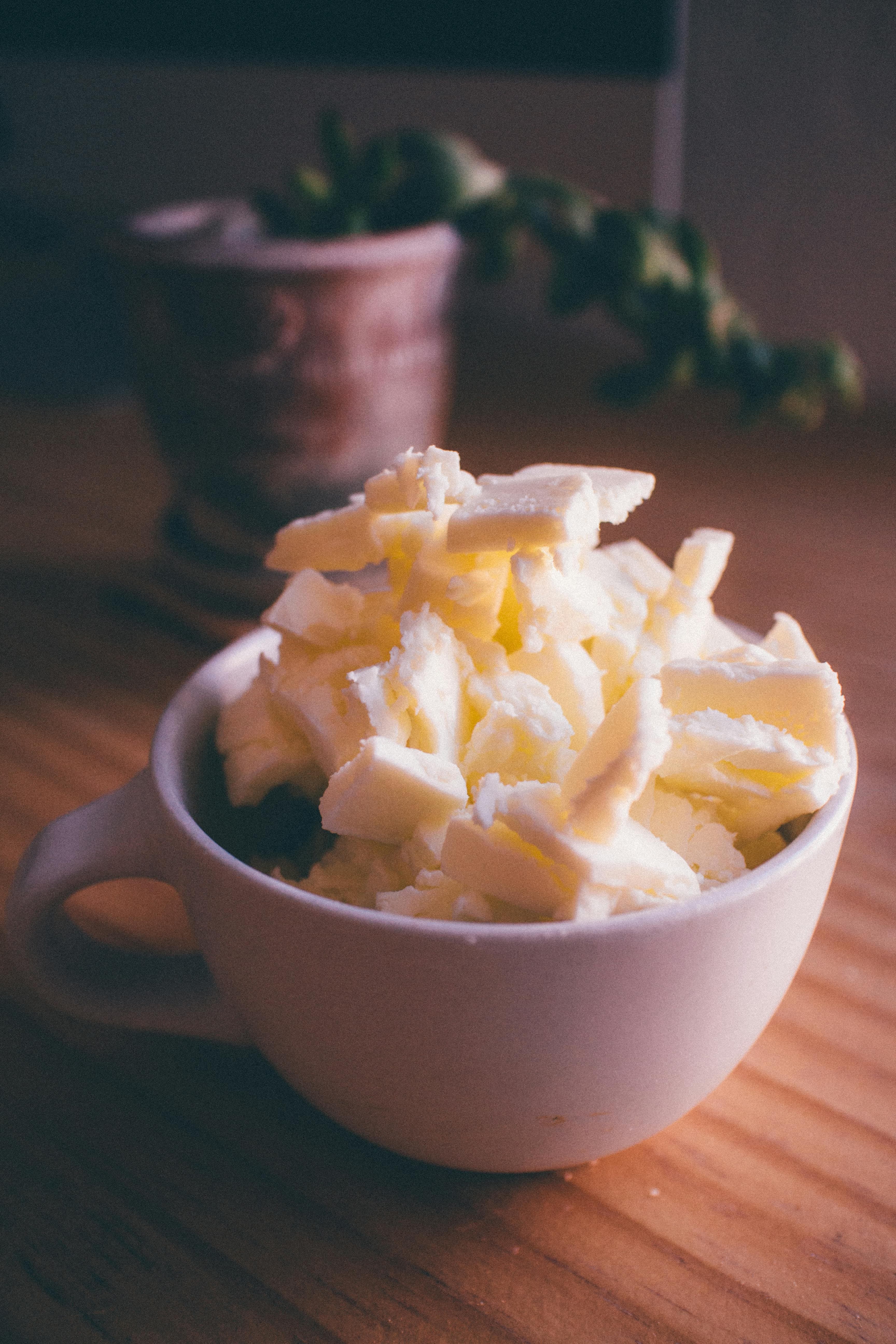 A coffee cup full of pats of butter on a wooden table.