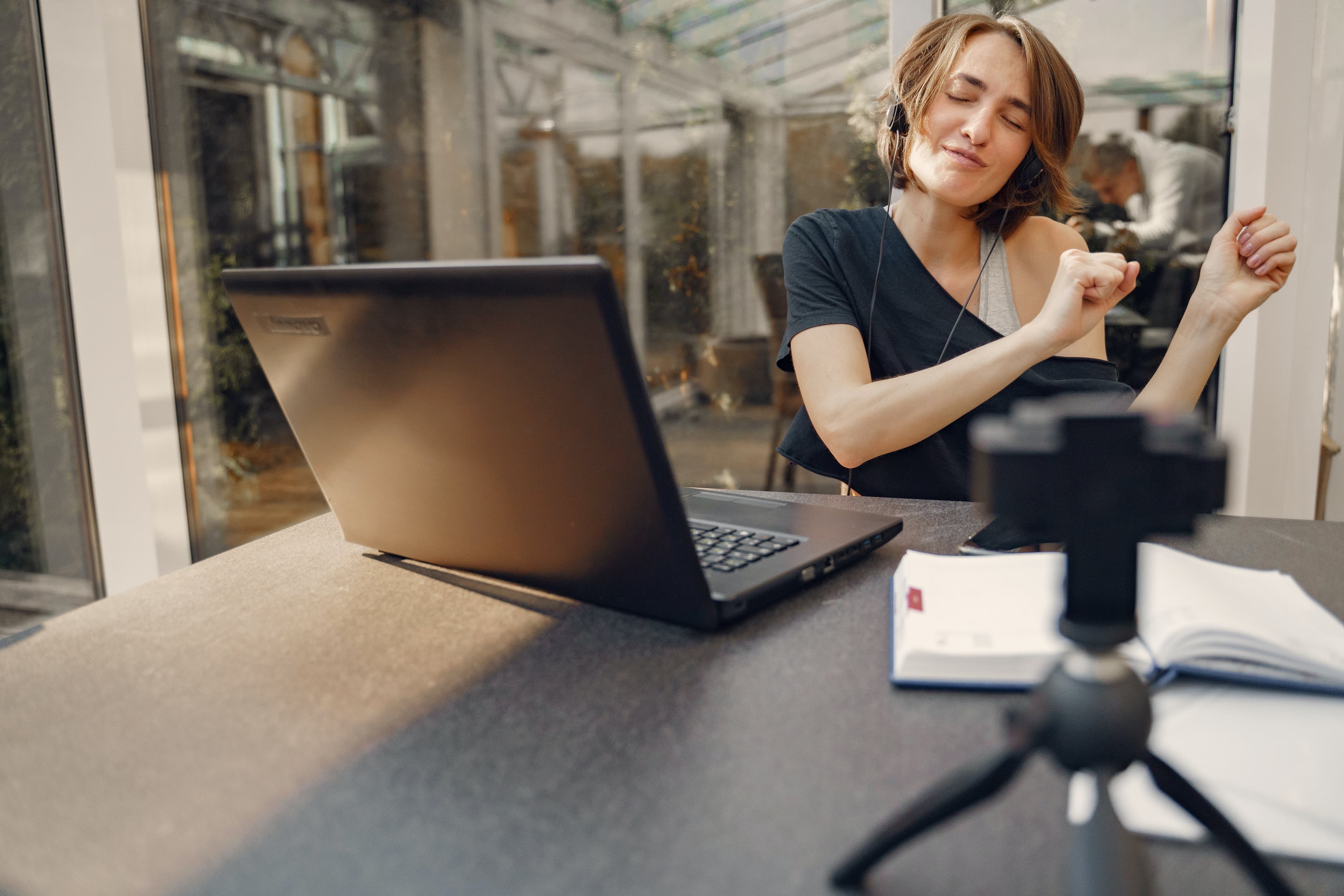 A woman dancing to music at a desk in front of a laptop