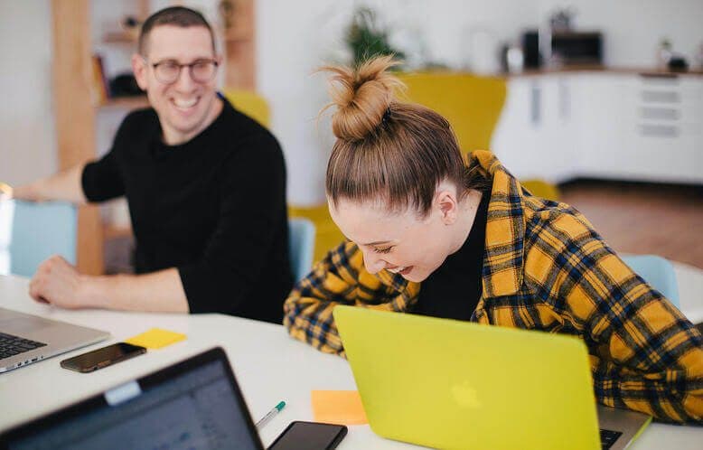 Two coworkers laughing together while working