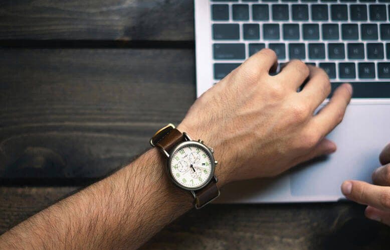 A hand on a laptop wearing a watch
