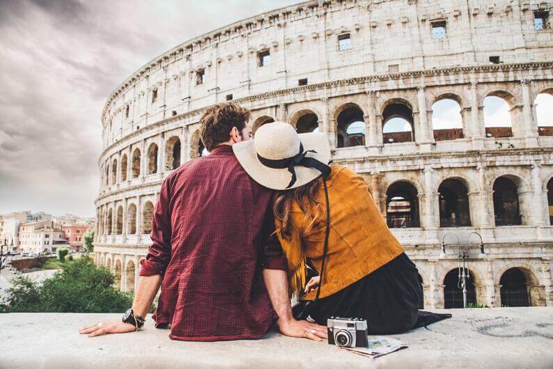 A couple of tourists sitting in front of the Colosseum in Rome