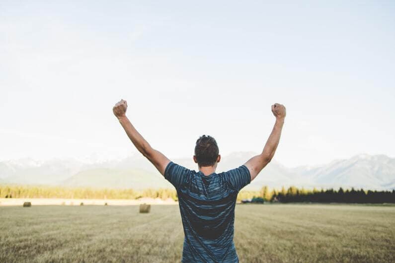 A man with his arms up in the air exulting