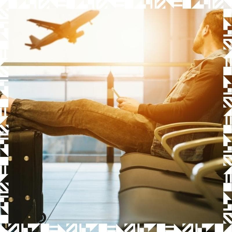 A person sitting in an airport waiting area resting with his feet up on a luggage