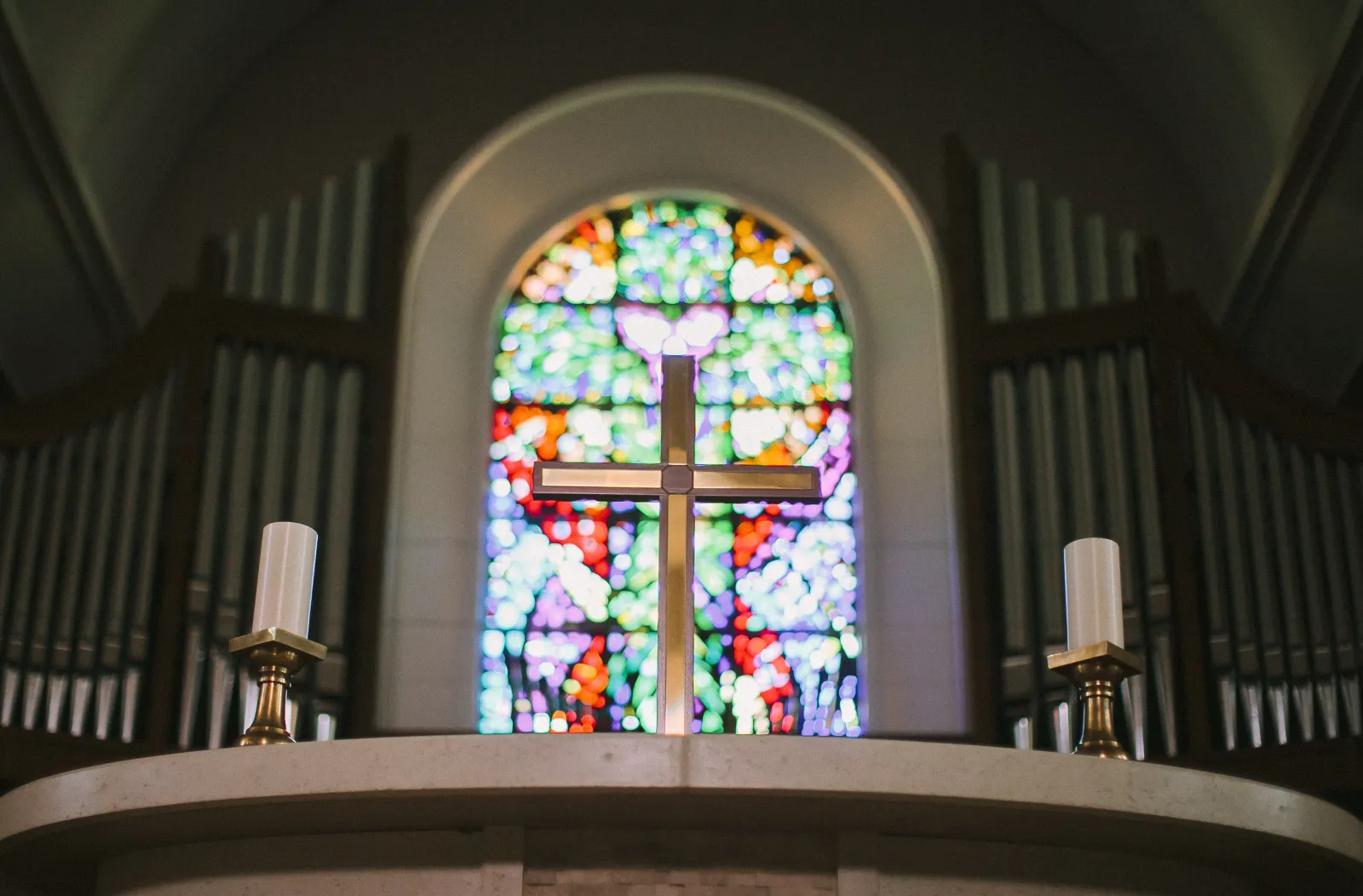 The interior of a Chaldean church, lit by a stained-glass window bearing a cross