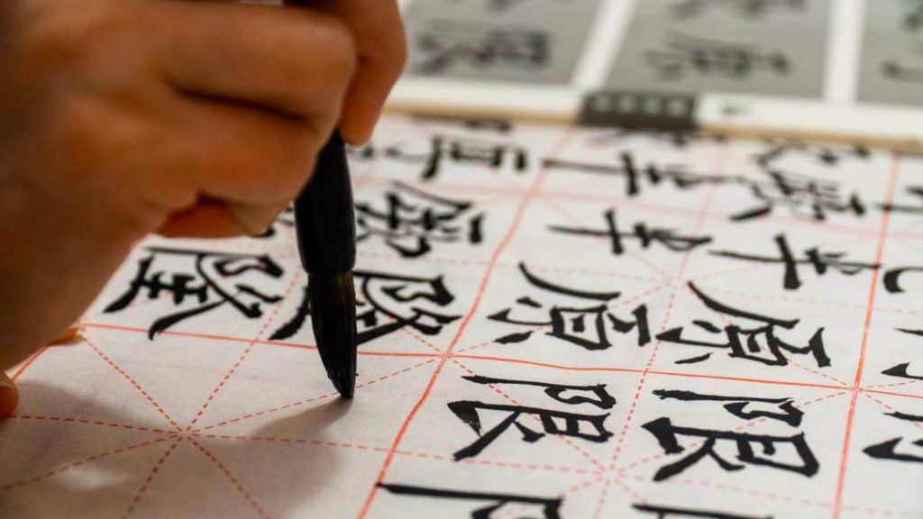 Image of a person writing Chinese characters on a piece of paper.