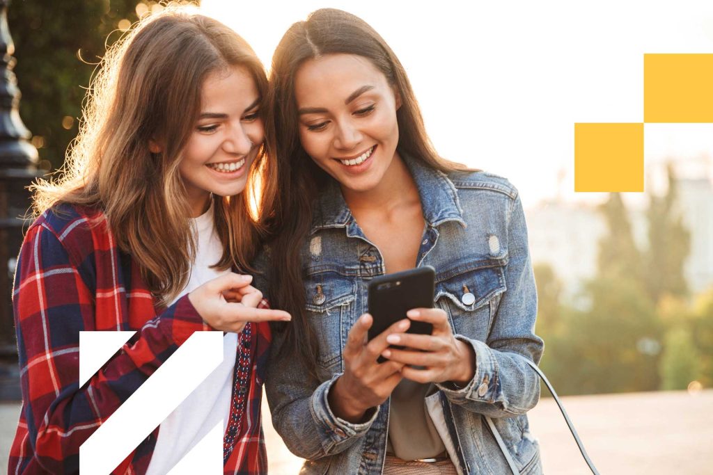 Two girls smiling and using phone